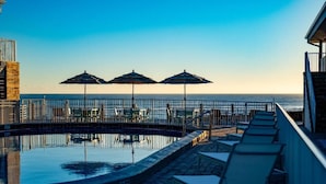 A pool area with lounge chairs and umbrellas, overlooking the ocean. - Melbourne Beach Resort & Surf Club  (Melbourne Beach)