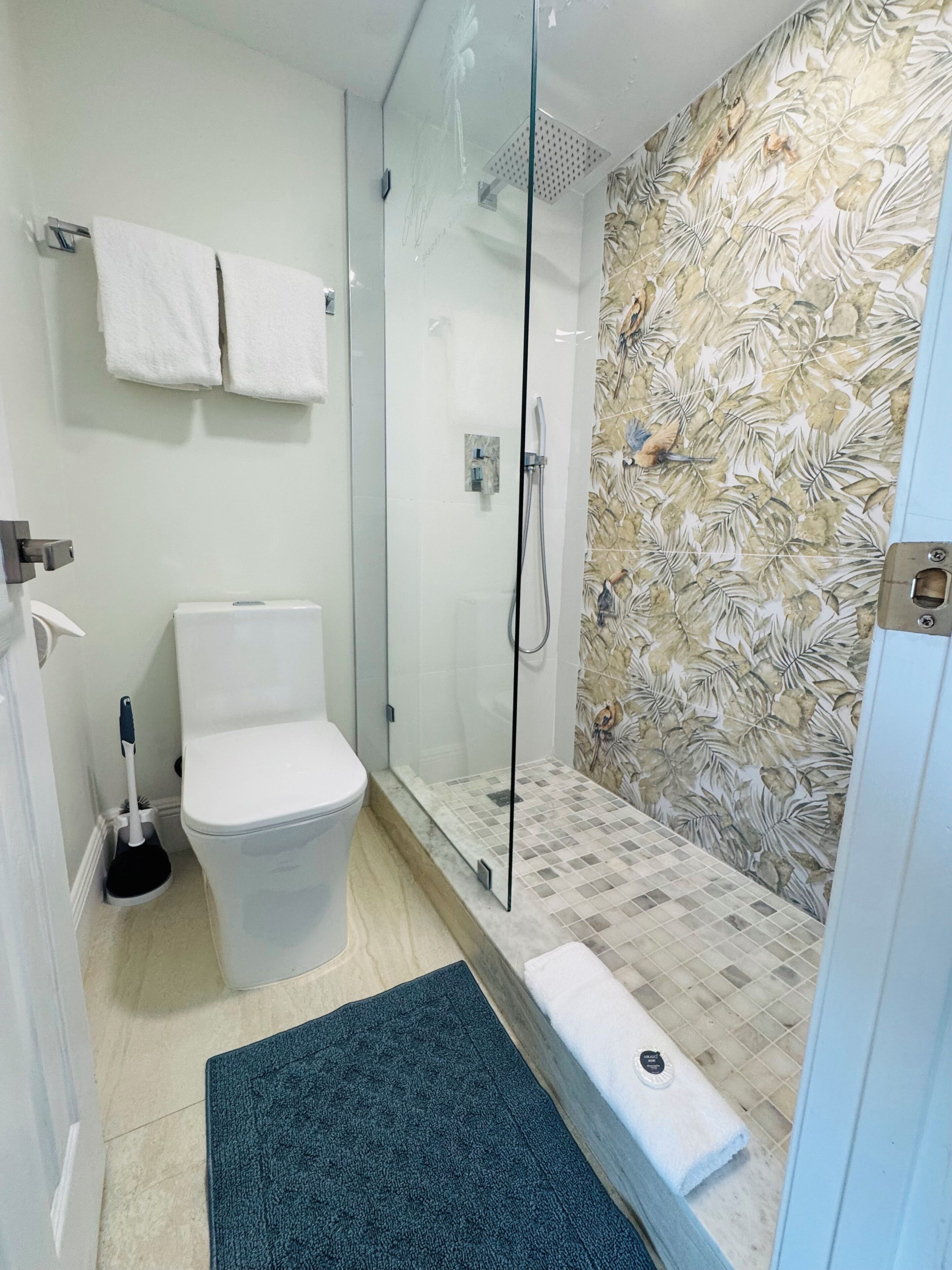 A bathroom with a glass-enclosed shower, a toilet, and a sink.