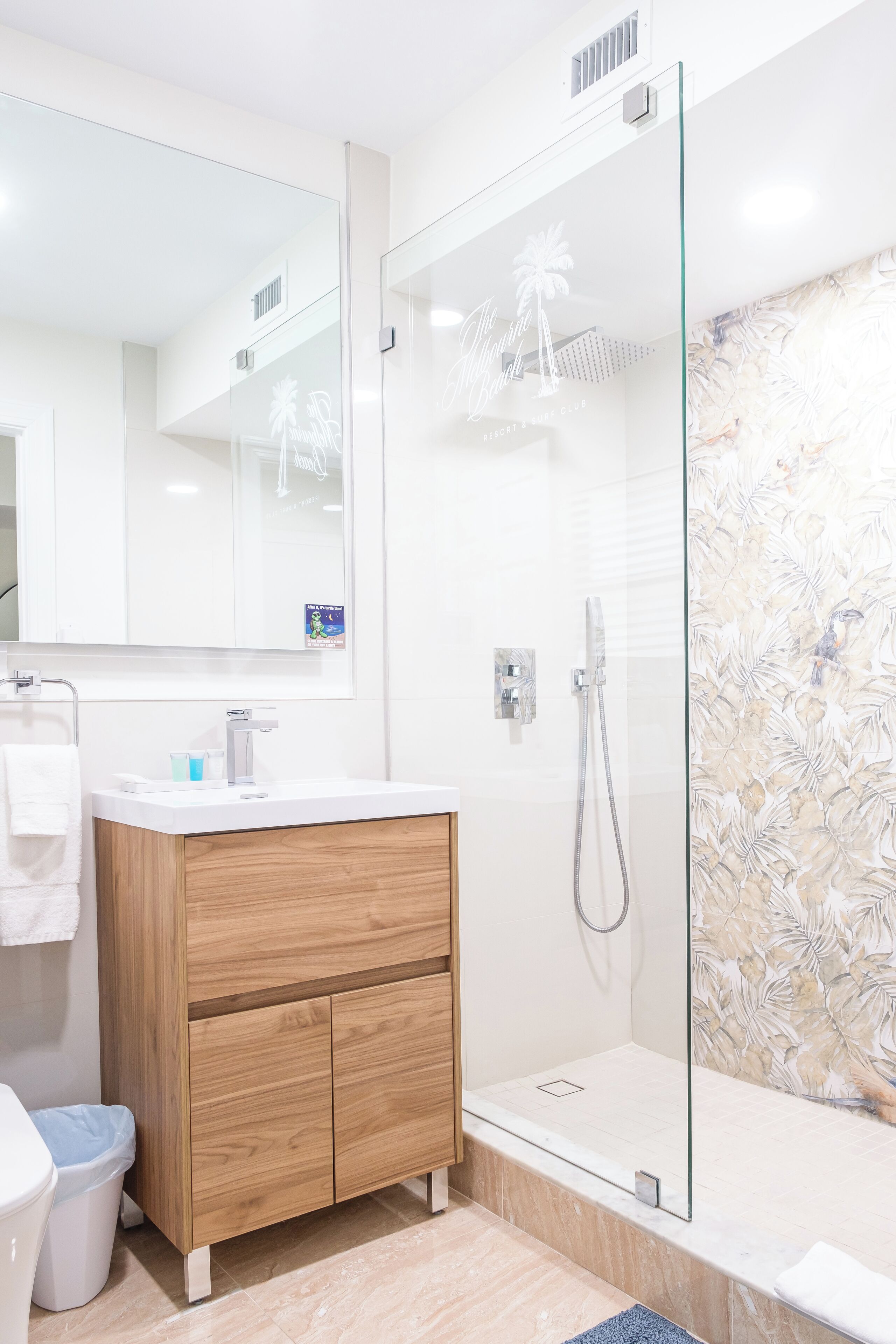 Une salle de bain moderne avec une douche à parois de verre, un meuble-lavabo en bois et un grand miroir.