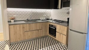 A modern kitchen with a black and white checkered floor, a stainless steel refrigerator, and a microwave above the stove. - PiazzaBolognaStay - beautiful home in Rome (Roma)