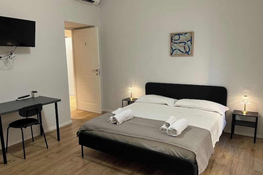 A bedroom with a bed, bedside tables, a desk, and a chair.