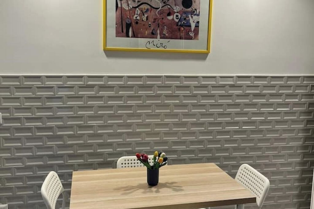 Zona pranzo con parete a effetto mattone, un'opera d'arte incorniciata e tavolo con sedie.