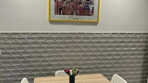 A dining area with a brick-patterned wall, a framed artwork, and a table with chairs. - PiazzaBolognaStay - beautiful home in Rome (Roma)