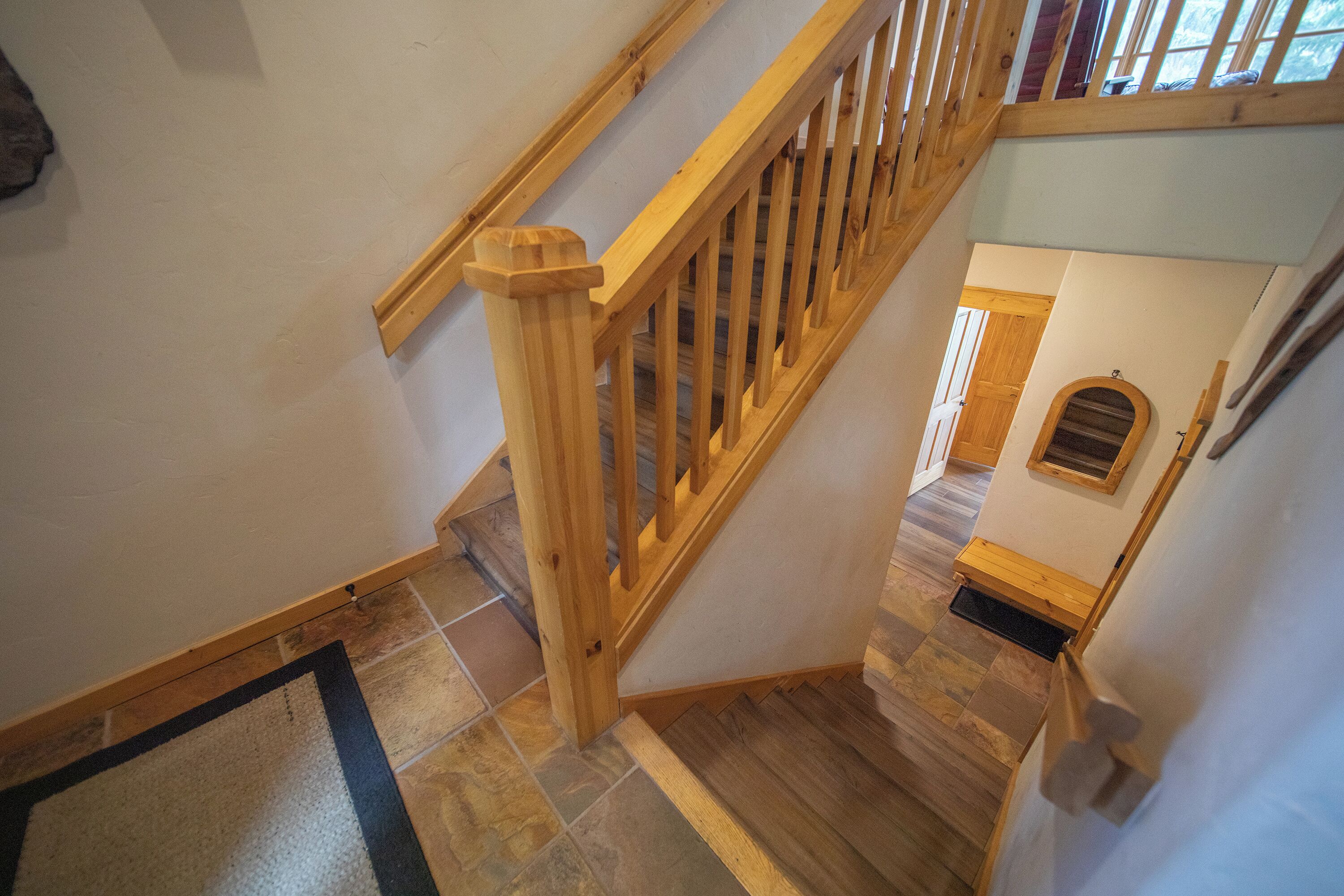 Una escalera de madera con barandilla que lleva a un rellano con una puerta y una pequeña ventana.
