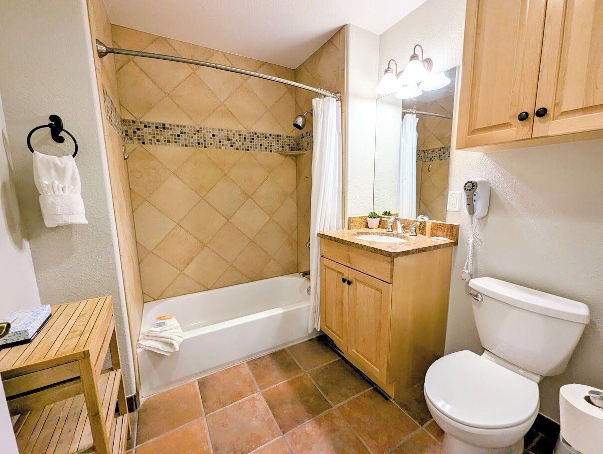 Een badkamer met bad, toilet, wastafel en douchegordijn.