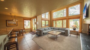A spacious living room with a large sectional sofa, a coffee table, and a dining area with bar stools. - Quicksilver 1635 (Keystone)