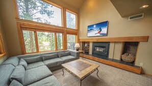 A living room with a sectional sofa, a fireplace, and large windows. - Quicksilver 1635 (Keystone)