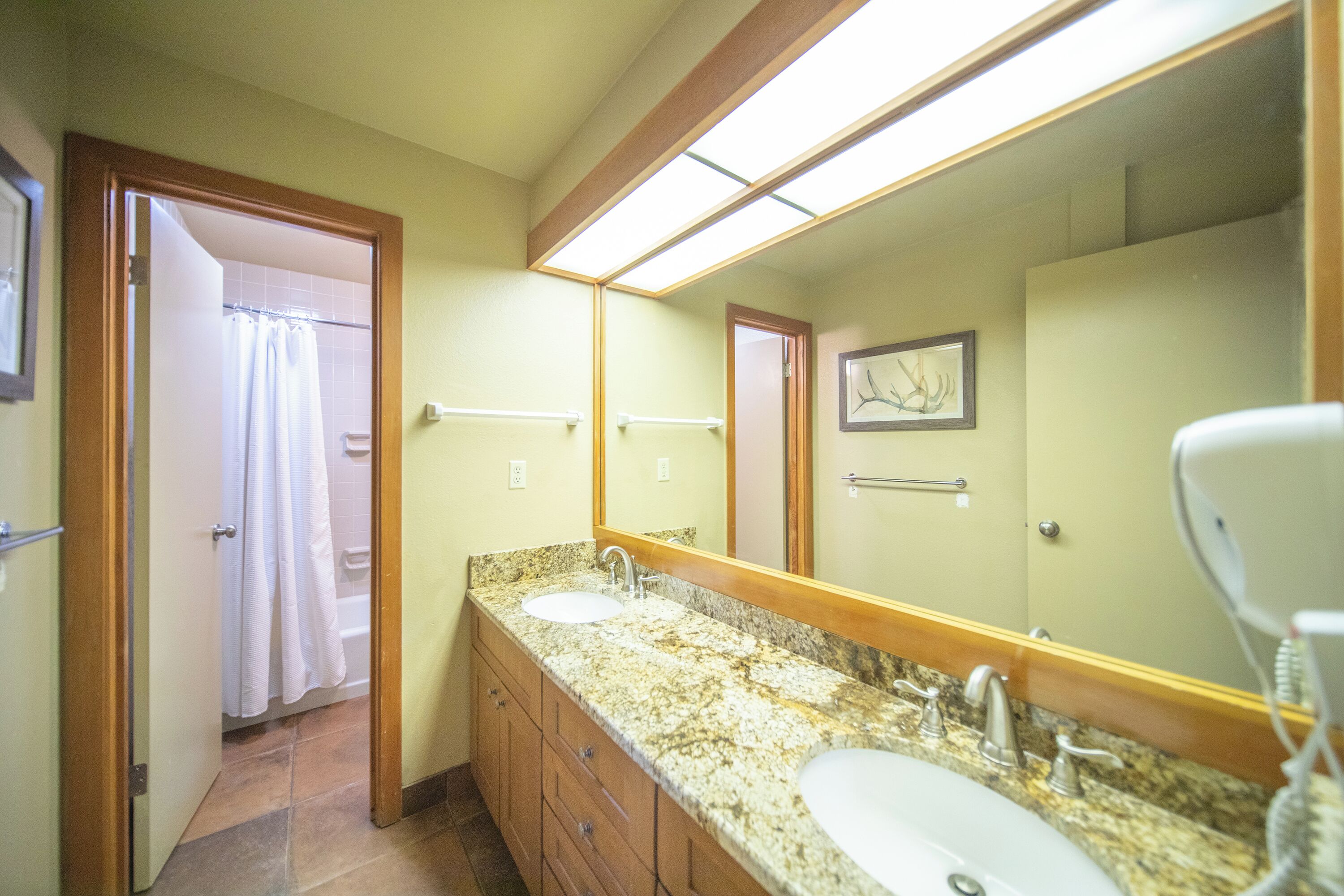 Une salle de bain avec deux lavabos, un grand miroir et un espace douche.