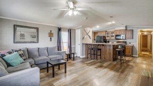 Un salon moderne avec un canapé gris, une table basse et un ventilateur de plafond.