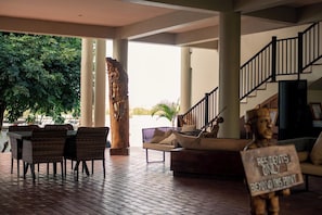 A covered outdoor area with wicker furniture, a wooden Buddha statue, and a sign indicating resident-only access. - Waters Edge By Serendib (Liwonde)