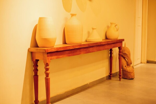 Una consola de madera con macetas de cerámica y una escultura frente a una pared.