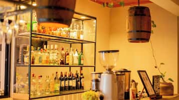 Un espace bar avec un assortiment de bouteilles d’alcool, une machine à café et un luminaire suspendu.