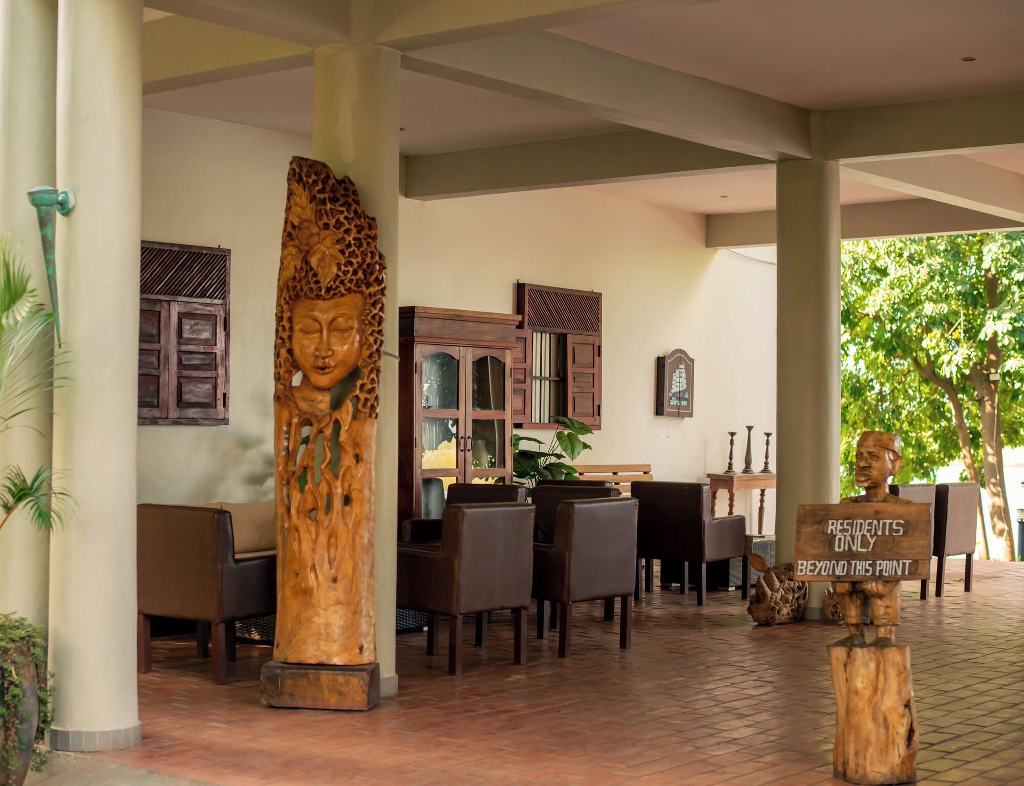 Un espace extérieur aménagé, abrité et doté de mobilier en bois, ainsi qu’une grande sculpture en bois et un panneau indiquant que l’accès est réservé aux résidents.