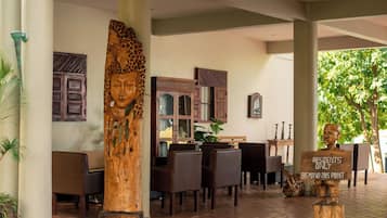 Un espace extérieur aménagé, abrité et doté de mobilier en bois, ainsi qu’une grande sculpture en bois et un panneau indiquant que l’accès est réservé aux résidents.