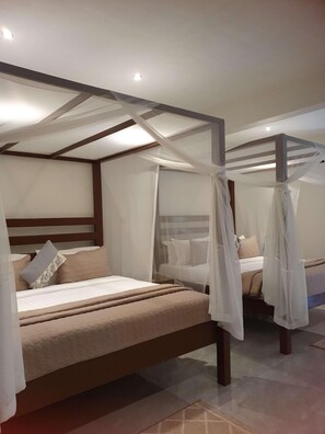 A bedroom with a canopy bed, a separate bed, and a nightstand. - Waters Edge By Serendib (Liwonde)