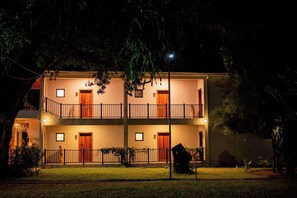 A two-story building with a balcony, a front door, and a small garden area. - Waters Edge By Serendib (Liwonde)