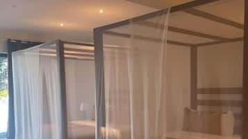 Ein Zimmer mit einem Himmelbett, bedeckt mit einem transparenten weißen Baldachin.