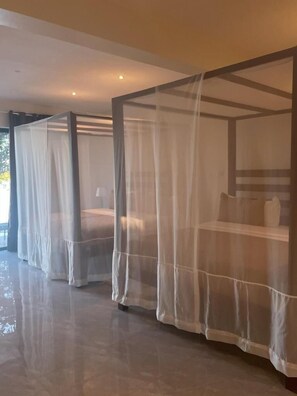 Habitación con cama con dosel cubierta por un dosel blanco translúcido.