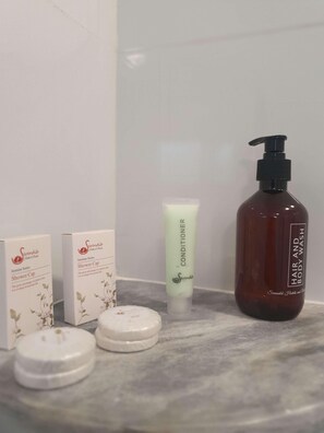 A bathroom counter with a shower cap box, a conditioner tube, and a body wash bottle. - Waters Edge By Serendib (Liwonde)