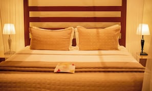 A neatly made bed with two pillows and a folded blanket, two bedside lamps, and a wooden headboard. - Waters Edge By Serendib (Liwonde)