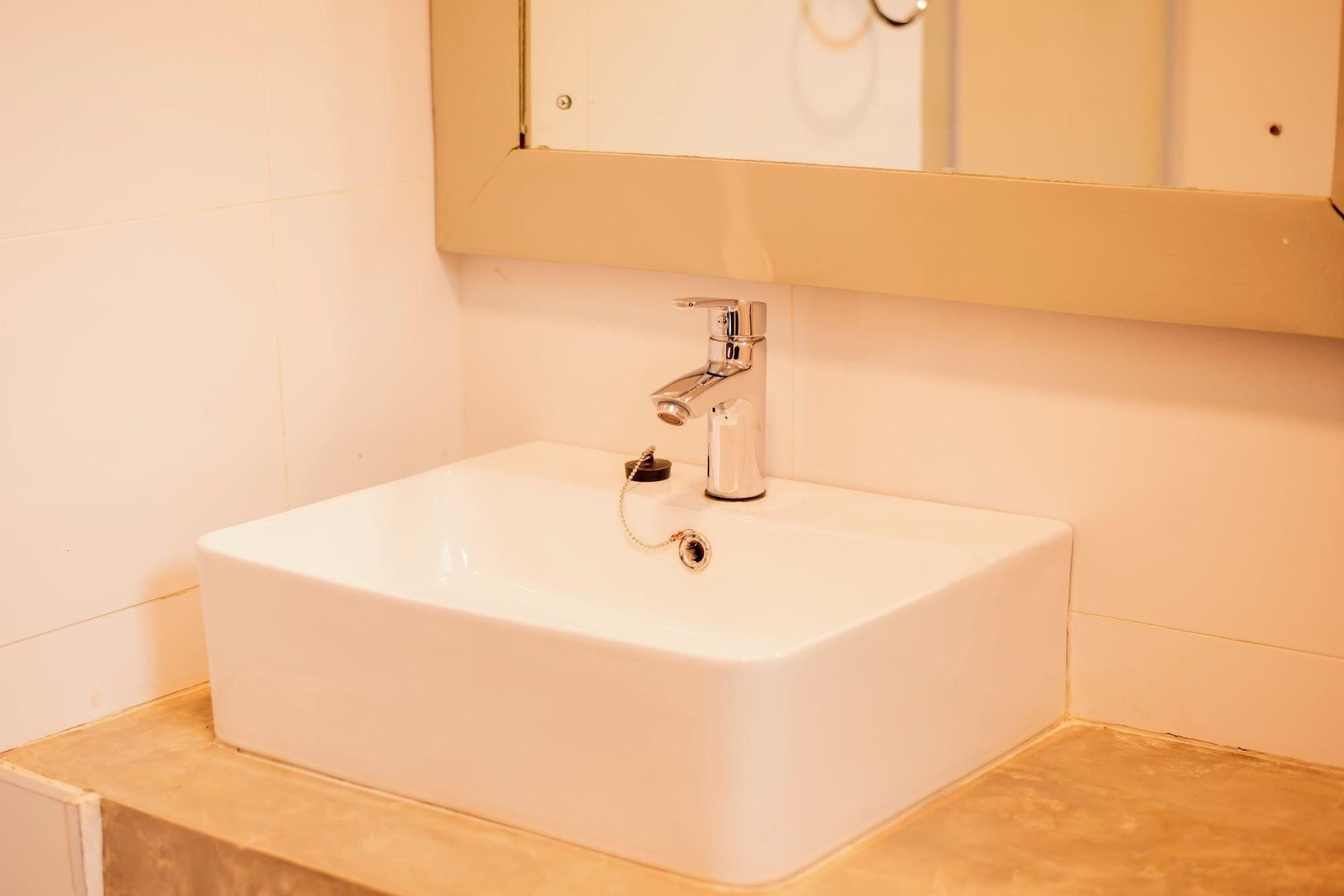 Un lavabo bianco con rubinetteria cromata e uno specchio sopra.