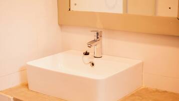 Un lavabo bianco con rubinetteria cromata e uno specchio sopra.