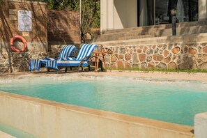 Un área de piscina con sillas de descanso y un flotador salvavidas.