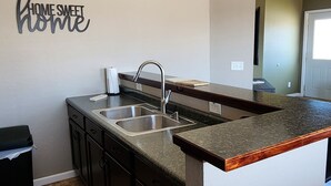 Et moderne køkken med mørke skabe, en granitbordplade og en backsplash.