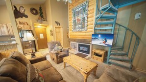 A cozy living room with a fireplace, a wooden coffee table, and a blue spiral staircase. - Flying Dutchman 1126 (Keystone)