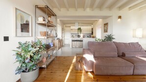 Una sala de estar moderna con piso de madera, un sofá grande, una mesita de centro y una planta en maceta.