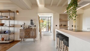 Una cocina moderna con una isla central, taburetes de bar y una planta colgante.