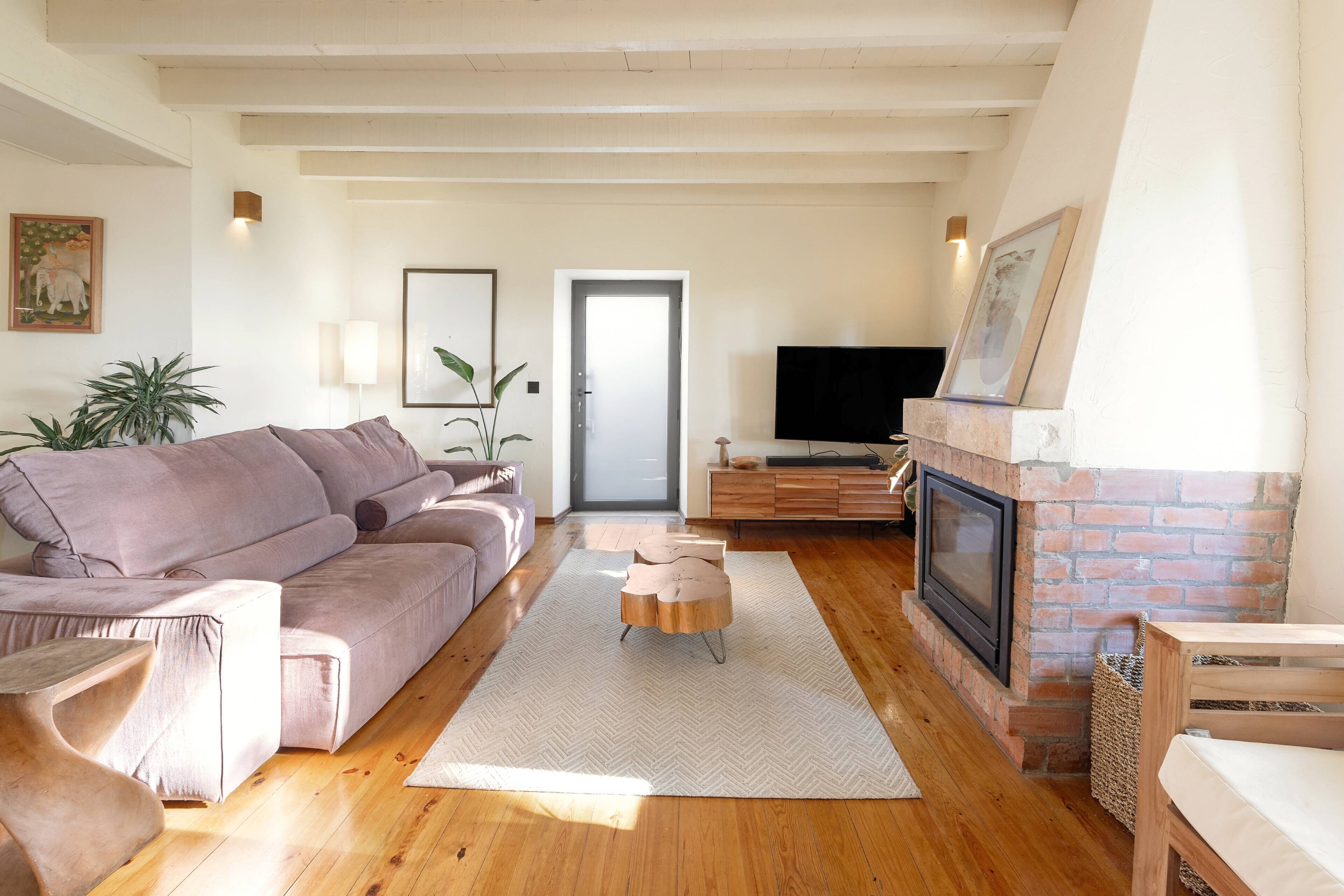 A living room with a sofa, a TV, a fireplace, and a door leading to another room.