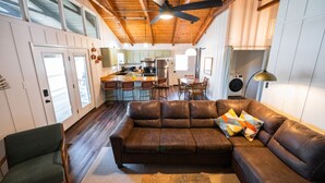 A cozy living room with a brown leather sofa, a green armchair, and a wooden ceiling fan. - “The Sugarloaf Mountain Cabin” A Charming Lakefront Escape!! (Higden)