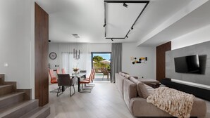 Una sala de estar moderna con un sofá, televisor y escalera.