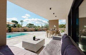 Ein moderner Außenbereich mit Pool, Sitzgelegenheiten und einer Steinwand.