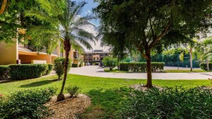 A courtyard with palm trees, a paved walkway, and a building with balconies. -  Marco Island Townhouse walking distance to South End Beach (Marco Island)