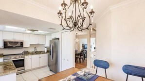 A modern kitchen with white cabinets, a stainless steel refrigerator, and a chandelier. -  Marco Island Townhouse walking distance to South End Beach (Marco Island)