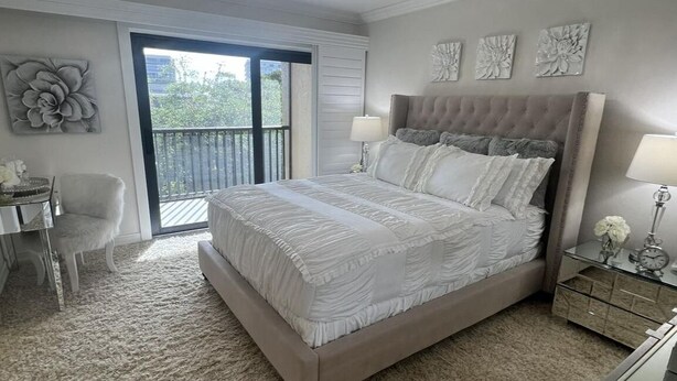 A bedroom with a large bed, a chair, a desk, and a balcony. -  Marco Island Townhouse walking distance to South End Beach (Marco Island)