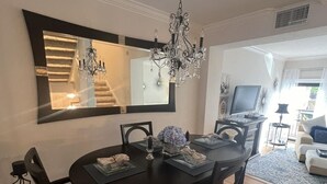 A dining area with a round table, dark chairs, a chandelier, and a large mirror above the table. -  Marco Island Townhouse walking distance to South End Beach (Marco Island)