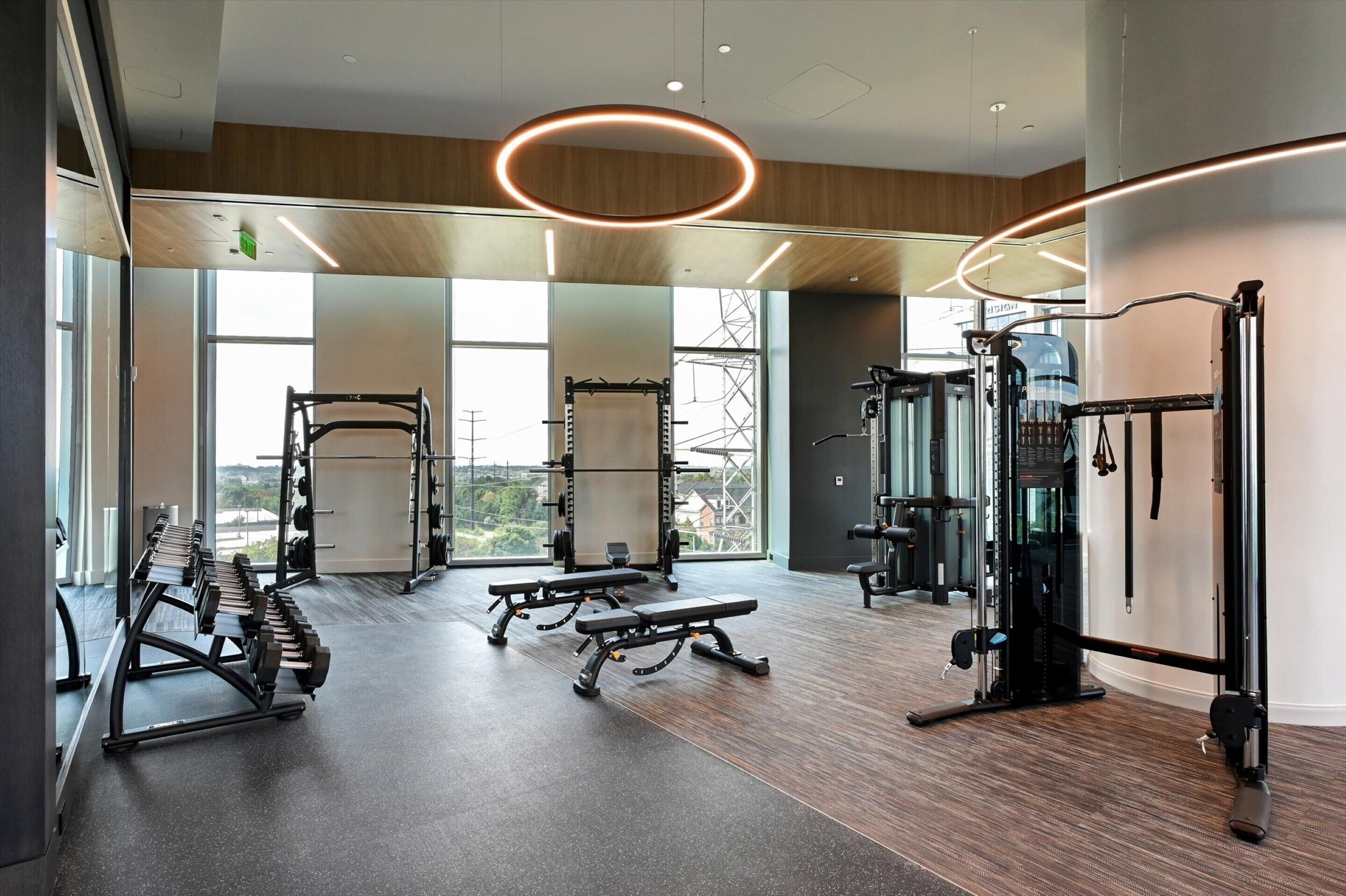 Une salle de sport moderne équipée de matériel de musculation, de bancs et d’un support pour les exercices de squat.