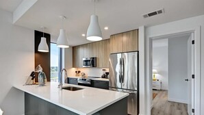 Una cucina moderna con una grande isola, elettrodomestici in acciaio inossidabile e illuminazione a sospensione.