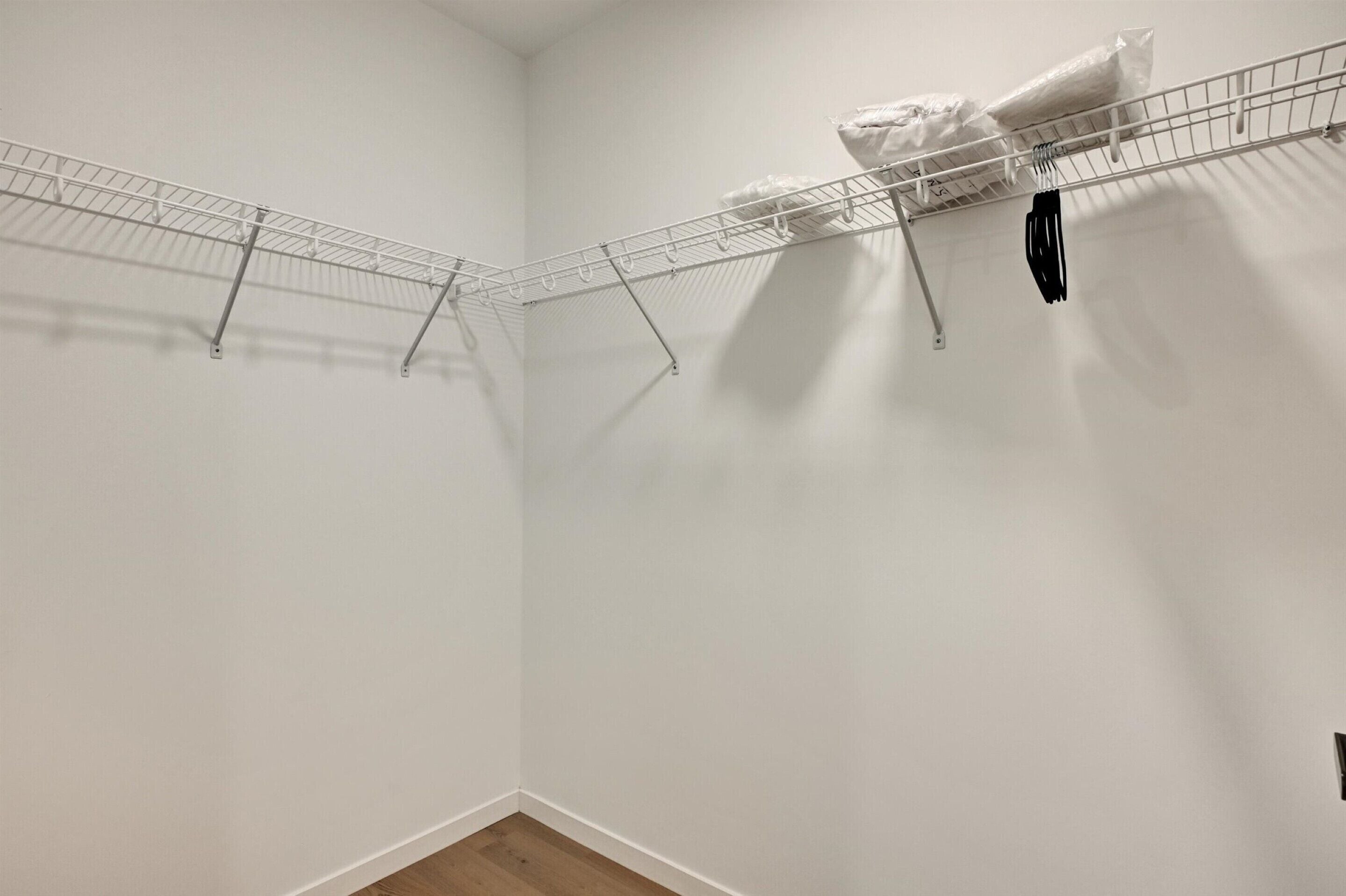 Quarto com parede branca e um varal de metal com uma toalha branca pendurada.