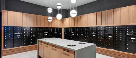 A modern locker room with wooden cabinets and black lockers, featuring a central island with sinks.