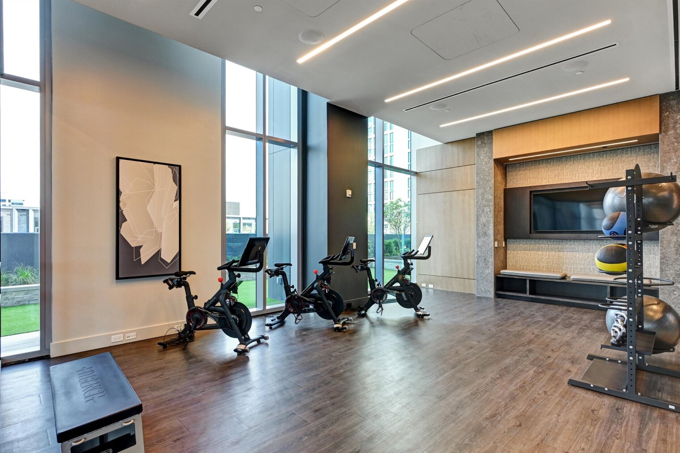 A modern gym with stationary bikes, a weight rack, and a bench.