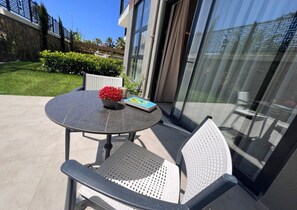 An outdoor patio with a round table, two chairs, a book, and a flower vase. - Ulu Residence Alanya (Alanya)