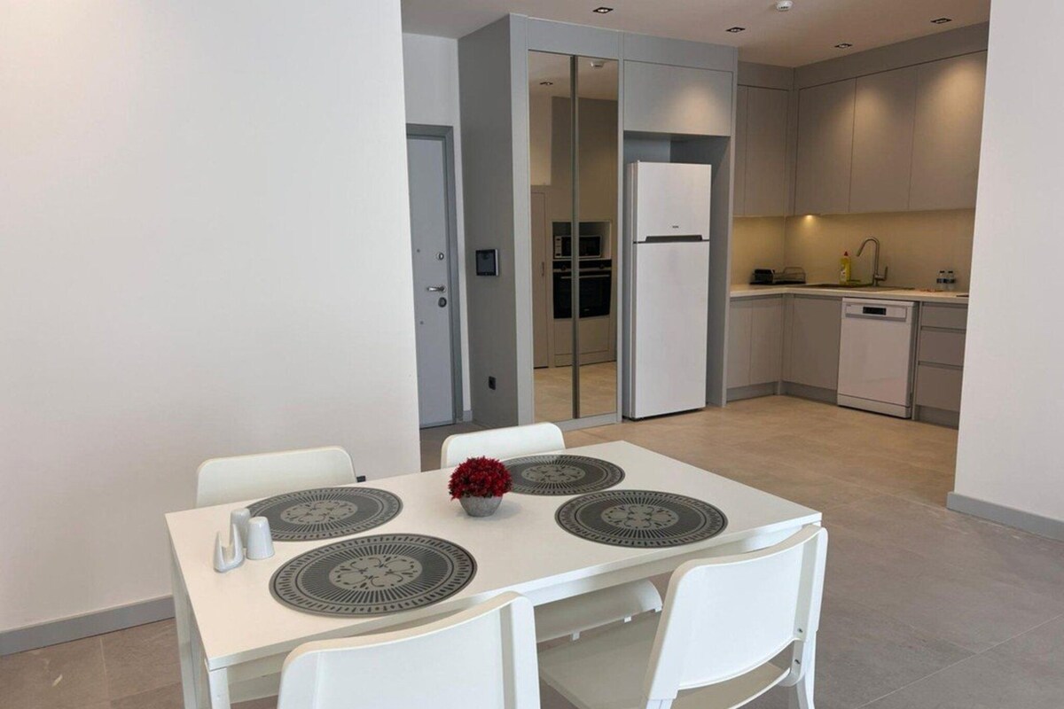 A modern kitchen with white cabinets, a built-in oven, and a dishwasher.