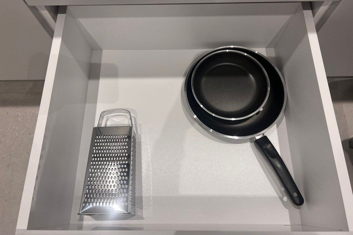A drawer containing a grater and a frying pan.