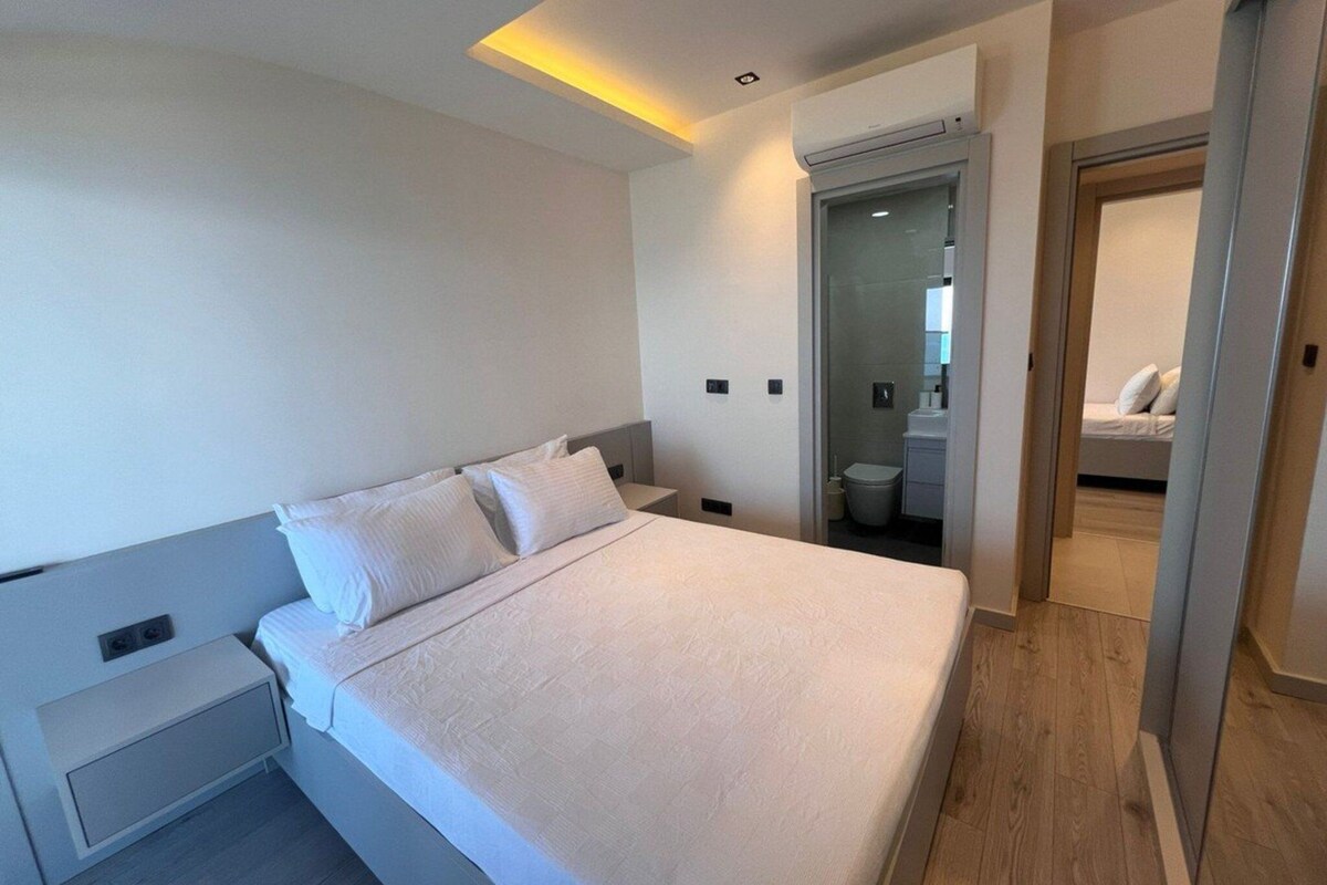 A modern hotel room with a large bed, a bedside table, and a walk-in closet.