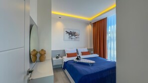 A modern hotel room with a large bed, a bedside table, a nightstand, and a wall-mounted mirror. - Ulu Residence Alanya (Alanya)