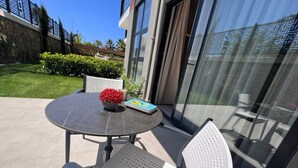 Eine Terrasse im Freien mit einem runden Tisch, zwei Stühlen, einem Blumentopf und einem Buch.